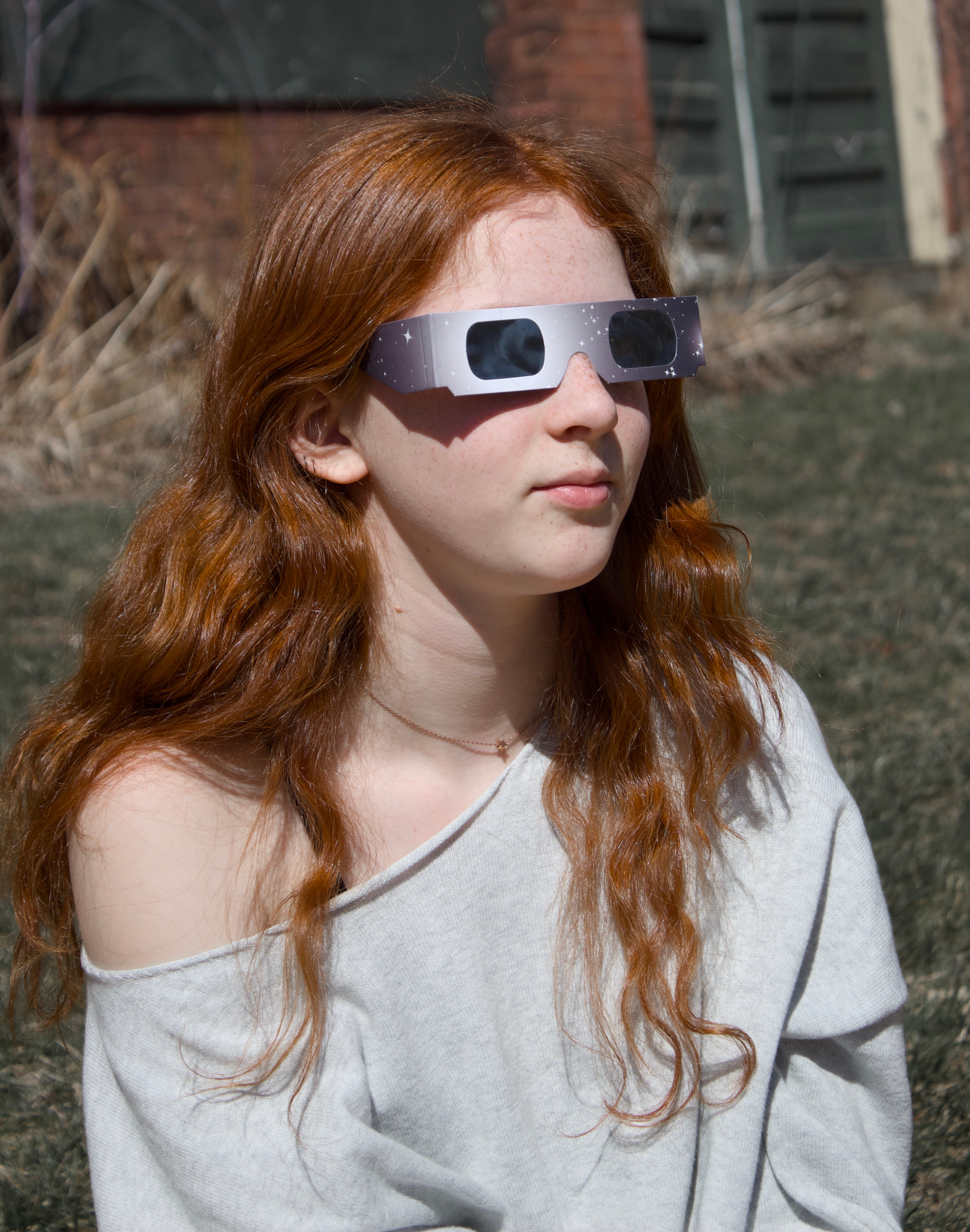 A photo of a girl wearing dark glasses looking at the sun.